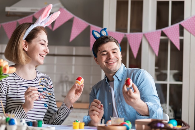 Happy mother and father painting eggs for easter