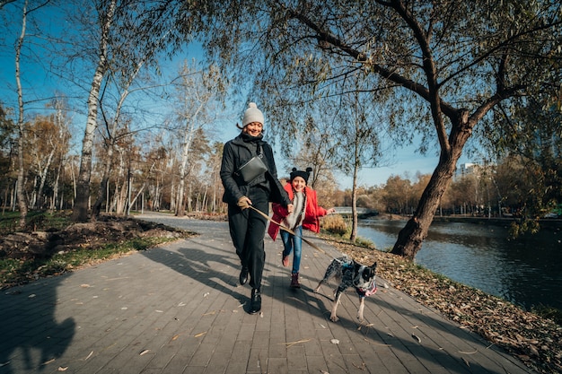 Free Photo happy mother and her daughter walk with dog in autumn park