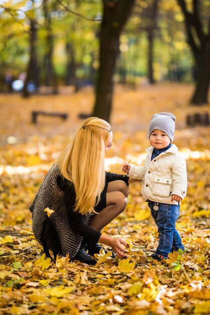 Happy mother and son are playing in the autumn park