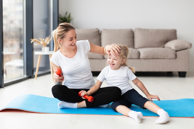 Happy mother with daughter on yoga mat at home