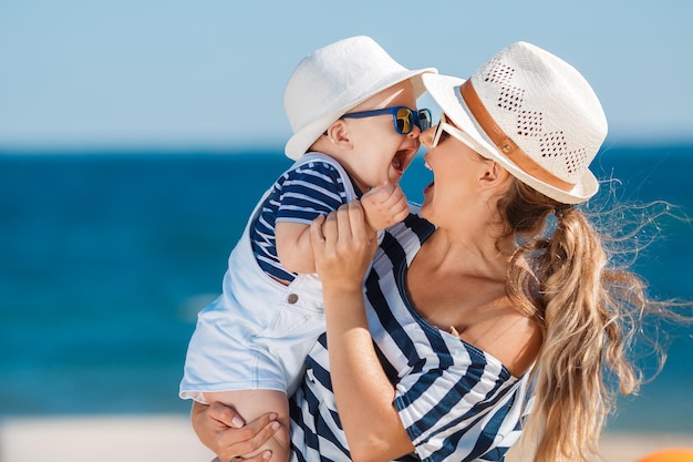 happy mother with little boy having fun on the beach near the sea