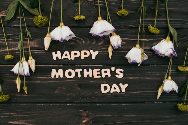 Happy Mothers Day inscription with flowers on table