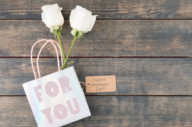 Free photo happy mothers day inscription with roses in paper bag