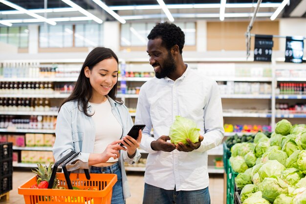 Happy multiethnical couple choosing goods in supermarket