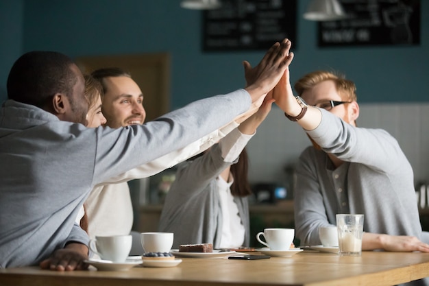 Happy multiracial friends cafe giving high-five at meeting in cafe