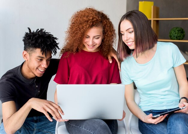 Happy multiracial male and female friends looking on digital tablet