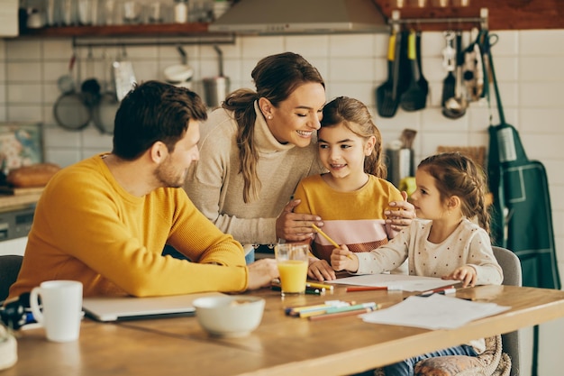 Free photo happy parents enjoying with their small daughters who are coloring on the paper at home