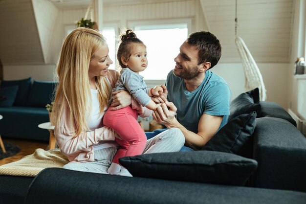 Happy parents having fun with their small daughter at home