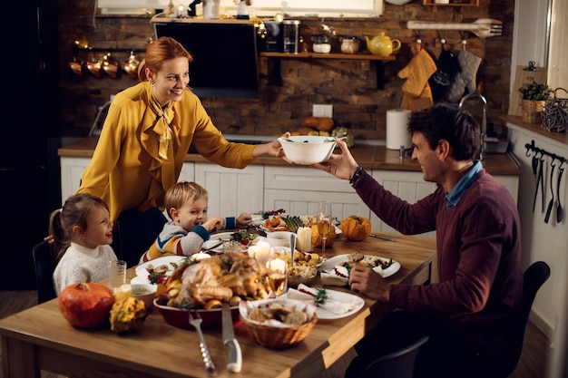 Happy parents with kids enjoying in Thanksgiving dinner in dining room