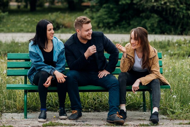 Happy people relaxing on bench and talking