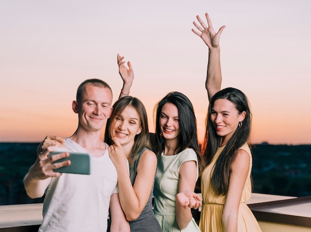 Happy people taking selfie at rooftop party