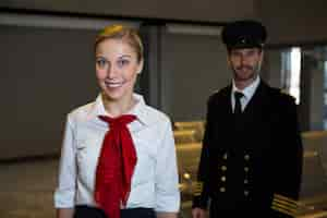 Free photo happy pilot and air hostess standing in the airport terminal