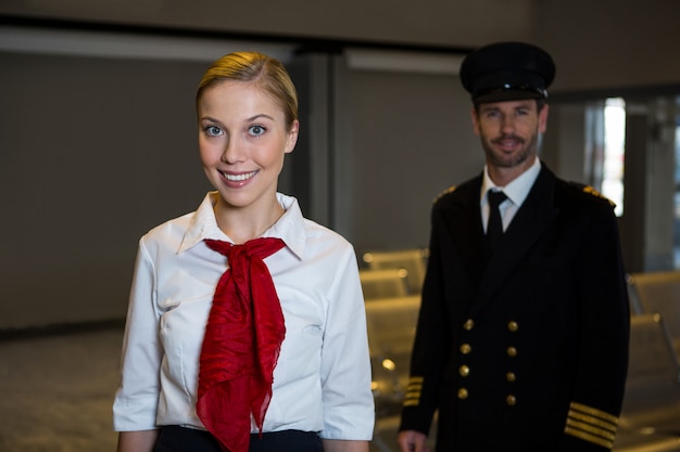 Free Photo happy pilot and air hostess standing in the airport terminal