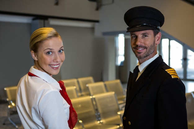 Free Photo happy pilot and air hostess standing in the airport terminal