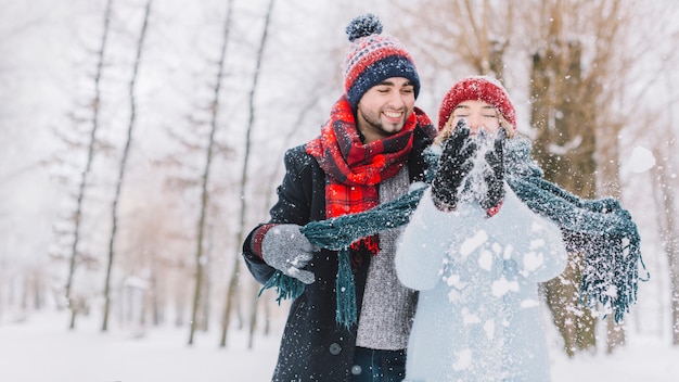 Happy playful couple throwing snow