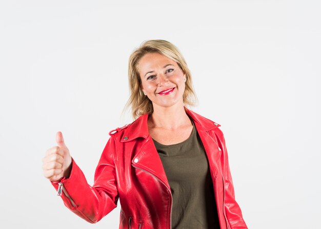 Happy portrait of a mature woman showing thumb up sign against white backdrop