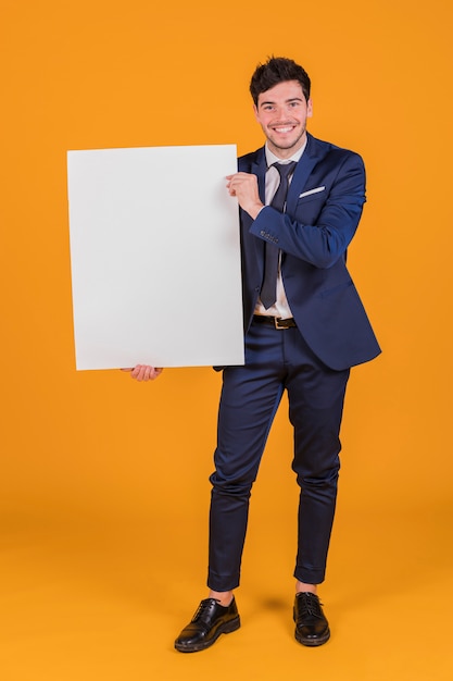 Free photo happy portrait of a young businessman showing white blank placard holding in hand