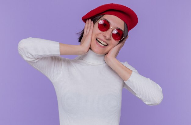 Happy and positive young woman with short hair in white turtleneck wearing beret