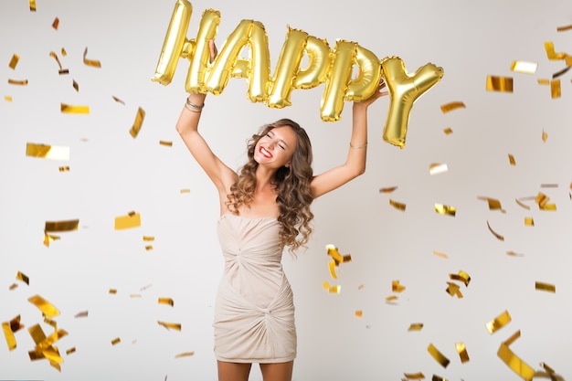 Happy pretty woman celebrating new year in golden confetti