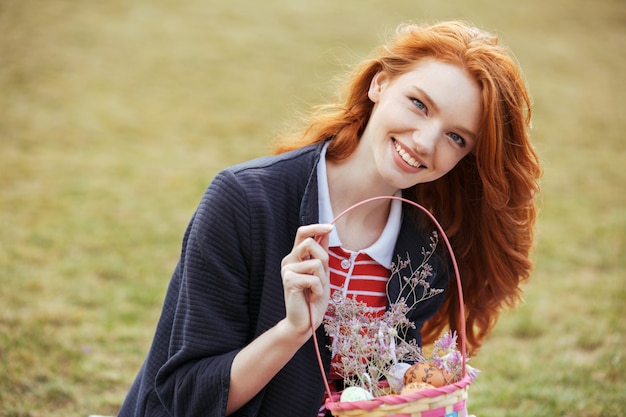 Free photo happy pretty woman holding picnic basket with easter eggs outdoors