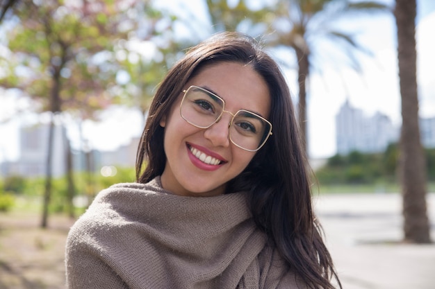 Happy pretty young woman posing at camera in city park