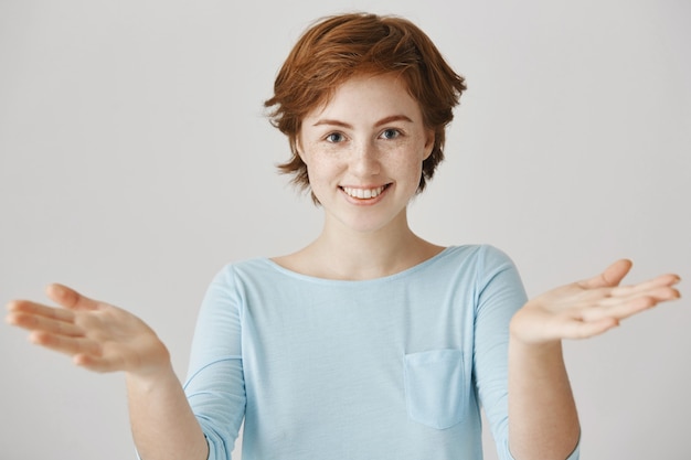 happy redhead girl posing against the white wall