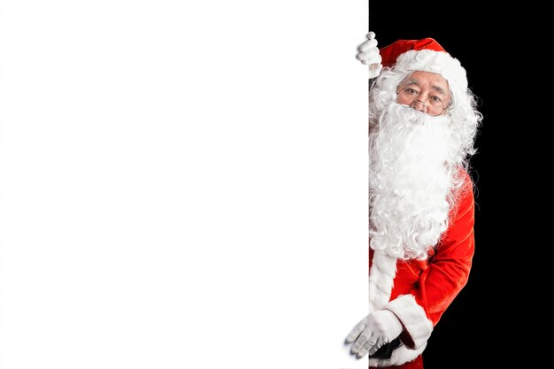 Happy Santa Claus holding blank advertisement banner background with copy space. Smiling Santa Claus pointing in white blank sign. Christmas theme, sales