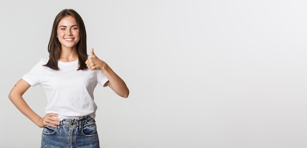 Happy satisfied young woman smiling showing thumbsup in approval like something