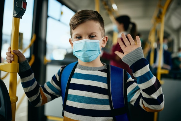 Free Photo happy schoolboy wearing protective face masks while commuting by bus