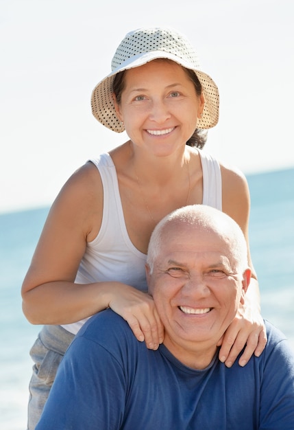 Happy senior guy and mature girl together against sea