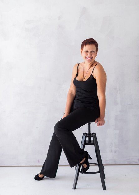 Happy senior lady sitting on a stool