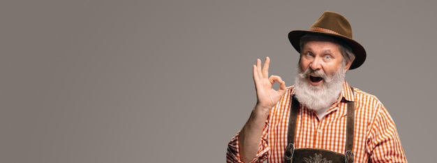 Happy senior man dressed in traditional Austrian or Bavarian costume gesturing