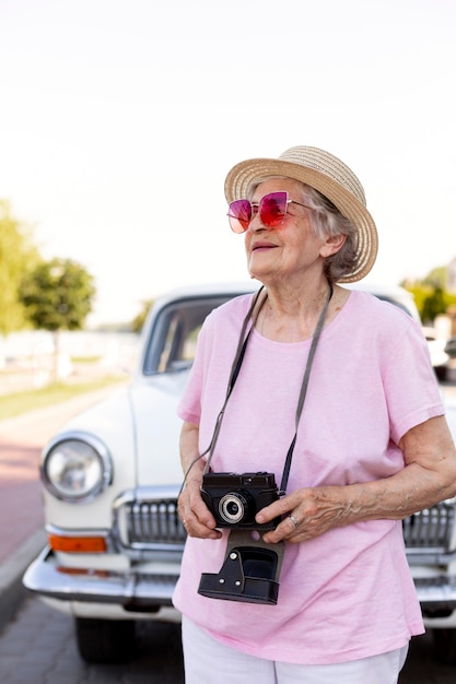 Free photo happy senior woman holding a camera while traveling