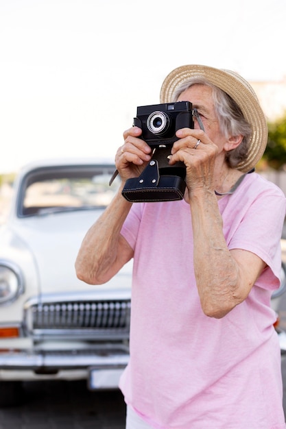 Happy senior woman holding a camera while traveling