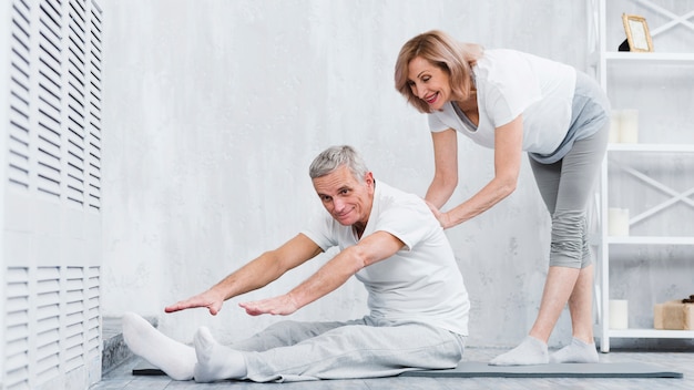 Happy senior woman at home helping pensioners couple to take correct position