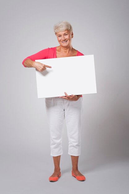 Happy senior woman pointing at whiteboard