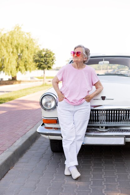 Happy senior woman standing next to her car