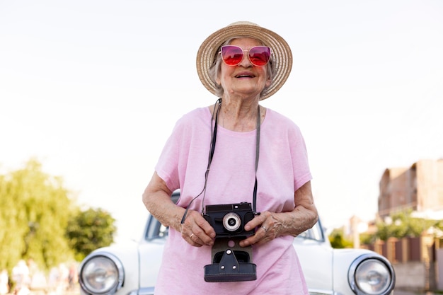 Happy senior woman standing next to her car