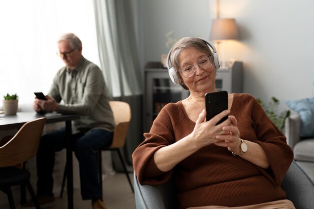 Happy senior woman using smartphone in the living room of a modern apartment