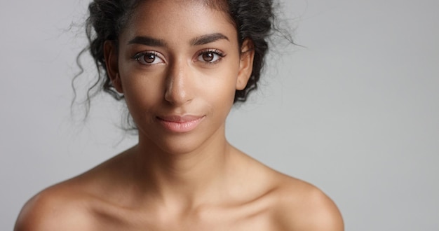 Happy serene young woman with beautiful olive skin and curly hair ideal skin and brown eyes in studio