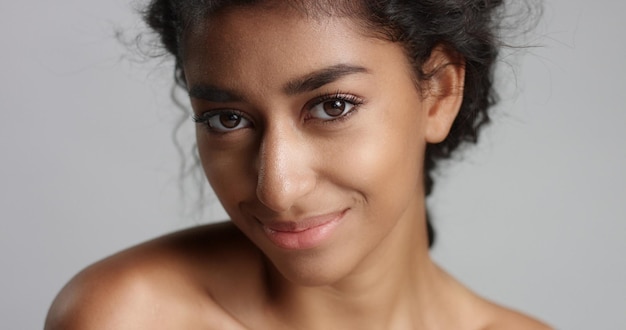 Free photo happy serene young woman with beautiful olive skin and curly hair ideal skin and brown eyes in studio