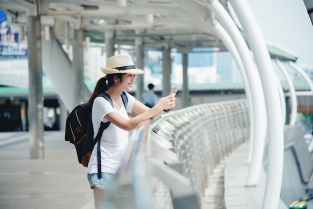 Happy smiling Asian student girl with backpack at city background