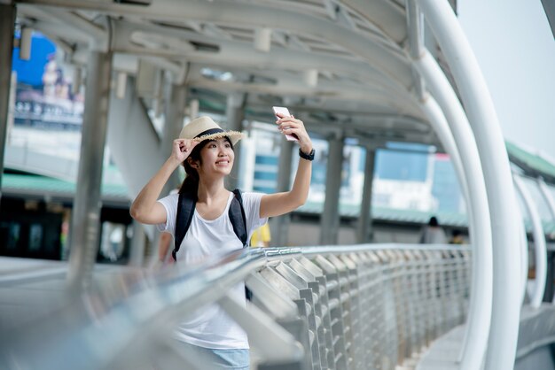 Happy smiling Asian student girl with backpack at city background