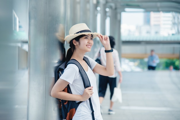 Happy smiling Asian student girl with backpack at city background