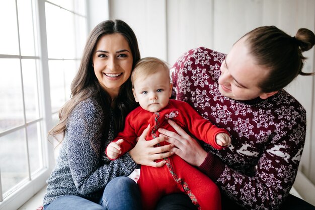 Happy smiling family at studio on background of the Christmas tree with gift