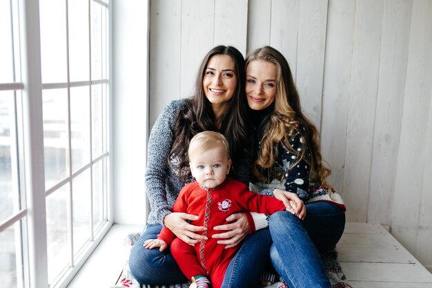 Happy smiling family at studio on background of the Christmas tree with gift