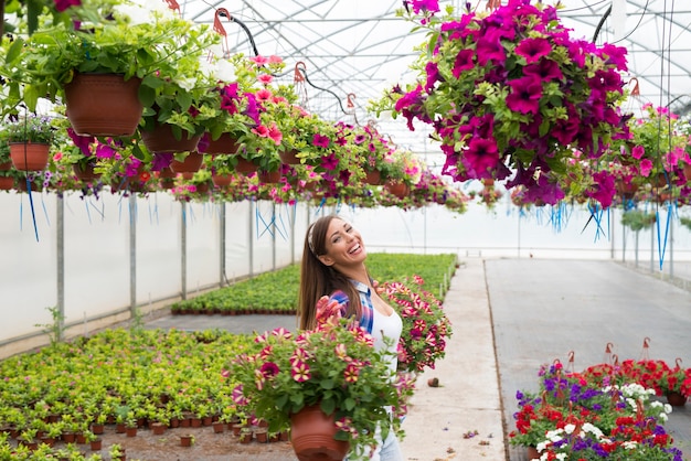 Happy smiling florist arranging flowers and enjoying work at greenhouse garden