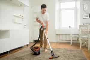 Free photo happy smiling man cleaning the carpet