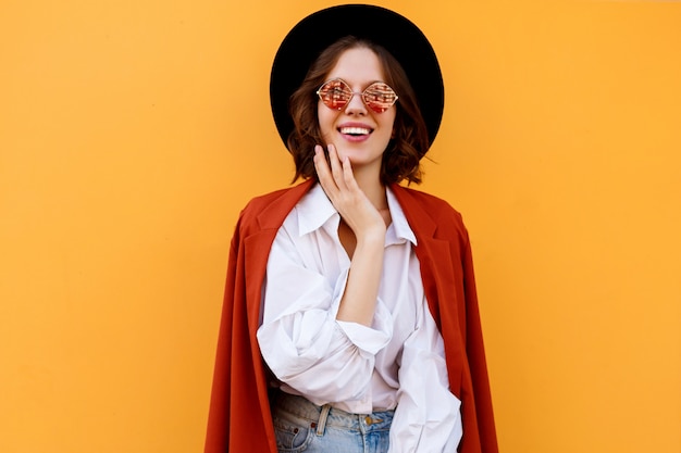 Free photo happy smiling short haired girl posing over yellow wall. warm colors. positive mood.