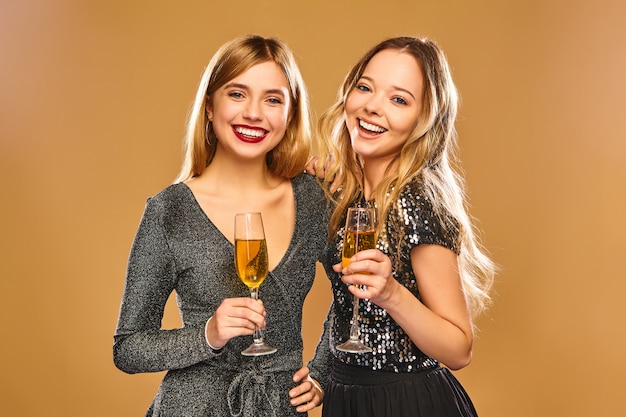 Happy smiling women in stylish glamorous dresses with champagne glasses